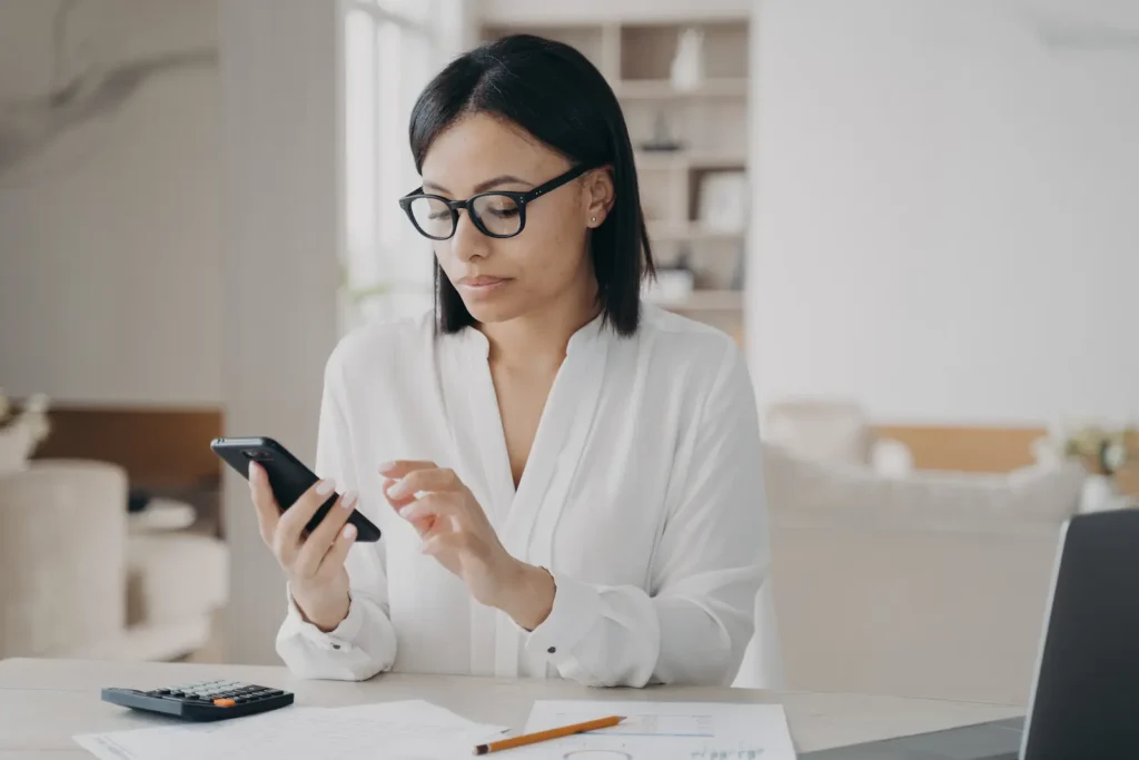Usuária alegre usando smartphone para gerenciar contas pessoais